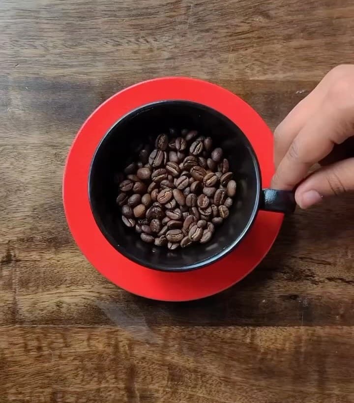A red cup filled with roasted coffee beans
